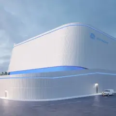 Nowoczesny budynek z logo GE Hitachi, prawdopodobnie elektrownia jądrowa BWRX-300, z niebieskimi akcentami świetlnymi.
