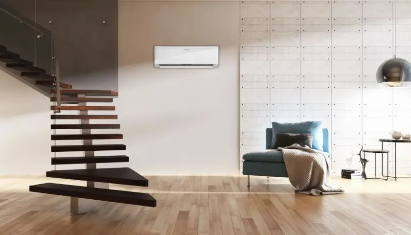Nowoczesna klimatyzacja split dyskretnie chłodzi wnętrze z drewnianymi schodami i wygodną kanapą.