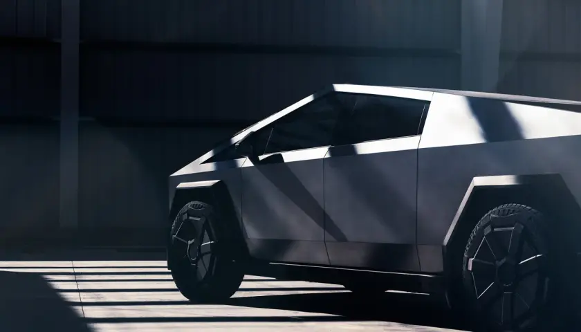 Futurystyczny Cybertruck Tesla w surowym wnętrzu, oświetlony promieniami słońca.
