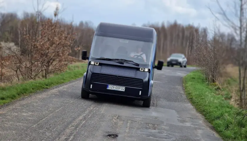 Nowoczesny polski samochód elektryczny przemierza wiejską drogę.