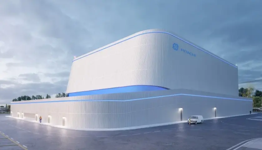 Nowoczesny budynek z logo GE Hitachi, prawdopodobnie elektrownia jądrowa BWRX-300, z niebieskimi akcentami świetlnymi.